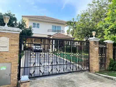 Charming two-story house with gated driveway and lush greenery