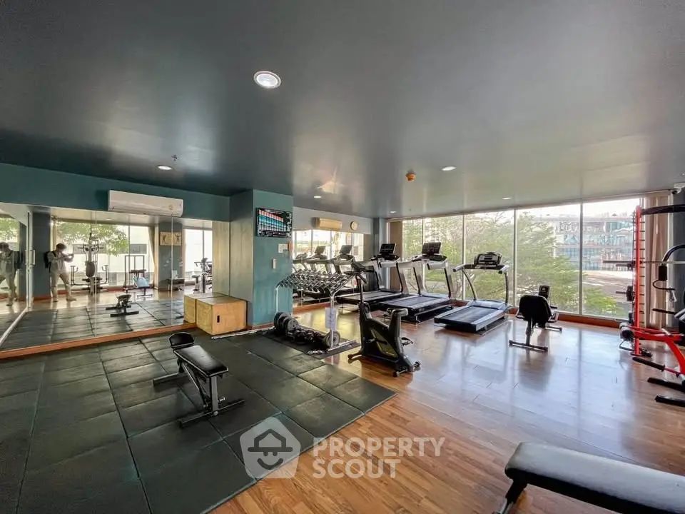 Spacious modern gym with large windows and fitness equipment in a residential building.