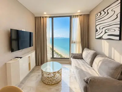 Stunning living room with ocean view, modern decor, and large window in beachfront property.
