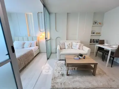 Modern studio apartment with stylish living area and cozy bedroom separated by glass partition.