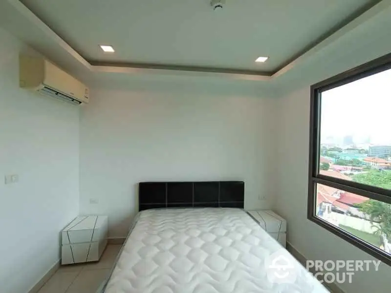 Modern bedroom with large window and air conditioning unit, offering a bright and airy atmosphere.