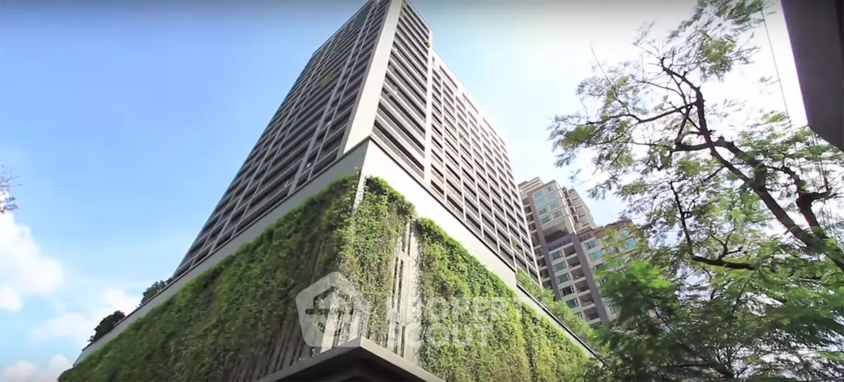 Modern high-rise building with lush vertical garden and clear blue sky