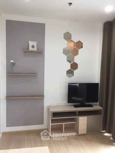 Modern living room with stylish decor and TV unit, featuring geometric wall art and floating shelves.