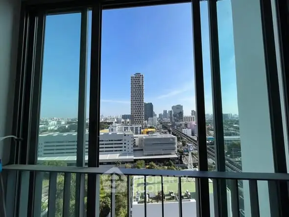 Stunning cityscape view from high-rise balcony with clear blue sky.