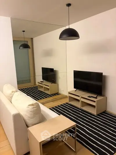 Modern living room with sleek TV setup and stylish black pendant lights.