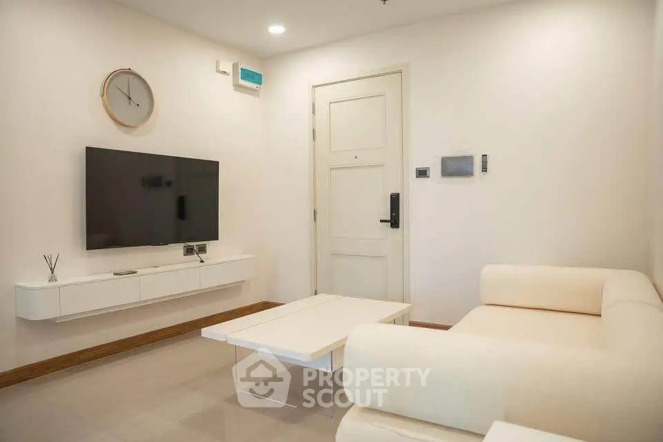 Modern living room with sleek furniture and wall-mounted TV, perfect for relaxation and entertainment.