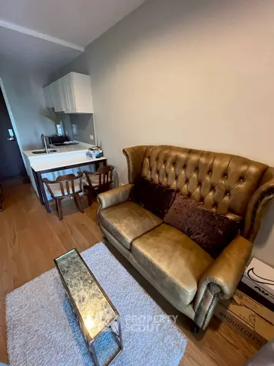 Charming living room with vintage leather sofa and modern kitchenette in cozy apartment.