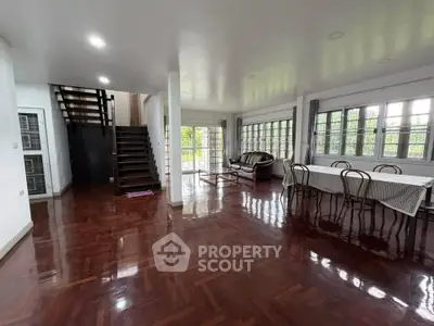 Spacious living room with elegant wooden flooring and large windows offering natural light.