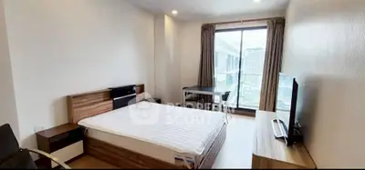 Spacious modern bedroom with large window and city view, featuring a comfortable bed and sleek furniture.