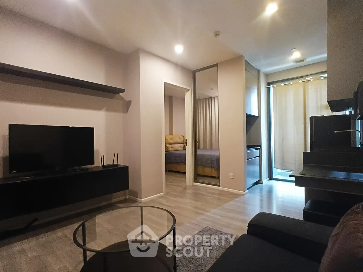 Modern living room with sleek furniture and open view into bedroom