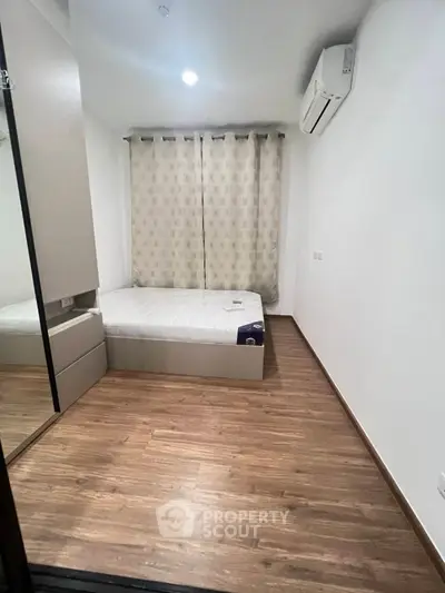 Cozy bedroom with wooden flooring and air conditioning, perfect for restful nights.