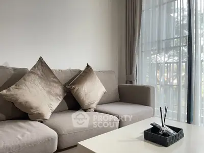 Modern living room with plush sofa and elegant decor, featuring large windows for natural light.
