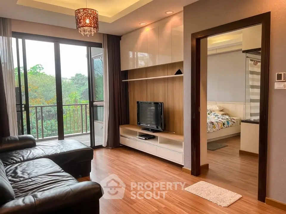 Modern living room with balcony view and adjacent bedroom, featuring sleek wooden flooring and stylish decor.