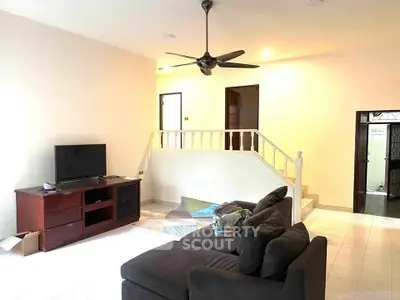 Spacious living room with modern decor and ceiling fan, perfect for relaxation and entertainment.