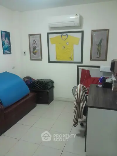Cozy study room with framed sports memorabilia and air conditioning, perfect for focused work or relaxation.