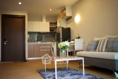 Modern living room with open kitchen, cozy sofa, and stylish decor