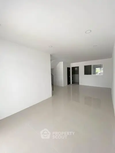 Spacious minimalist living room with glossy tiled floors and ample natural light