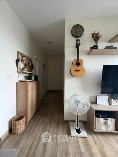 Cozy living room with wooden flooring, guitar decor, and modern furnishings.