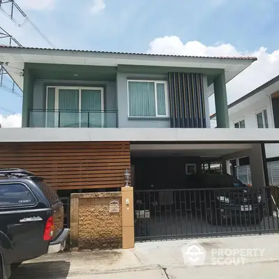 Modern two-story residence with sleek design, featuring a wooden facade and spacious covered parking, set under a clear blue sky.