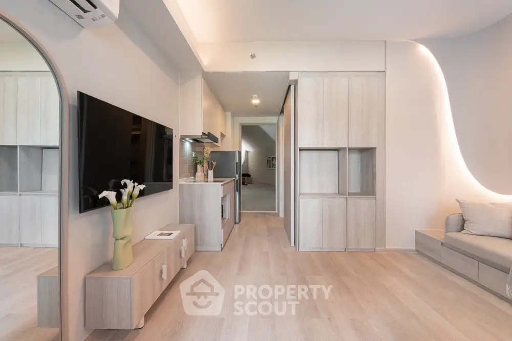 Modern living room with sleek design and neutral tones, featuring a large TV and stylish furniture.