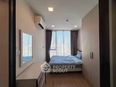 Modern bedroom with large window and city view, featuring sleek furniture and air conditioning.