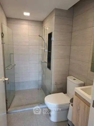Modern bathroom with glass shower and sleek fixtures in contemporary apartment.