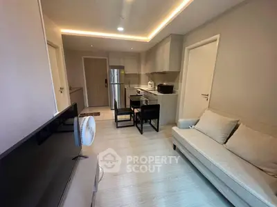 Modern open-layout living room with kitchen, featuring sleek furniture and ambient lighting.