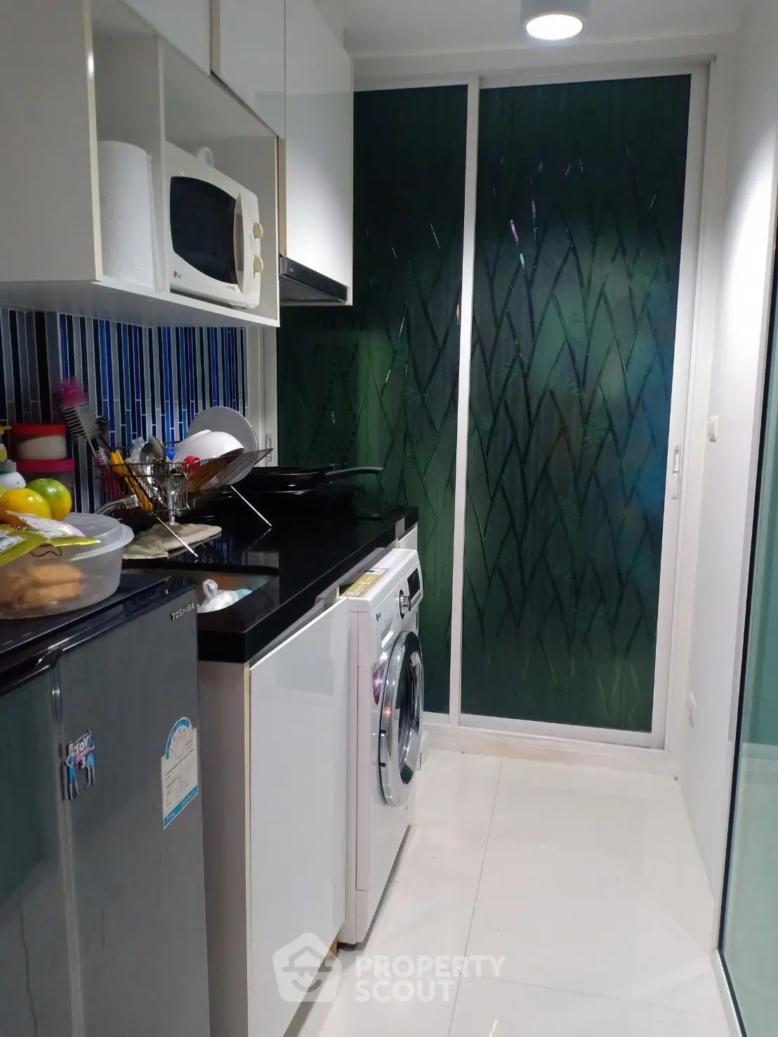 Modern kitchen with sleek appliances and stylish backsplash in a compact layout.