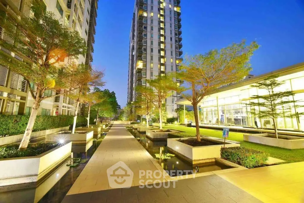 Luxurious modern apartment complex with stunning landscaped gardens and water features at dusk.