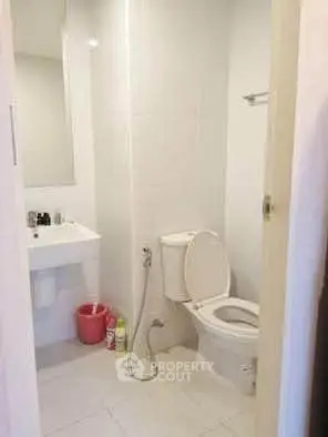 Compact bathroom with white fixtures and minimal design, featuring a toilet and sink.