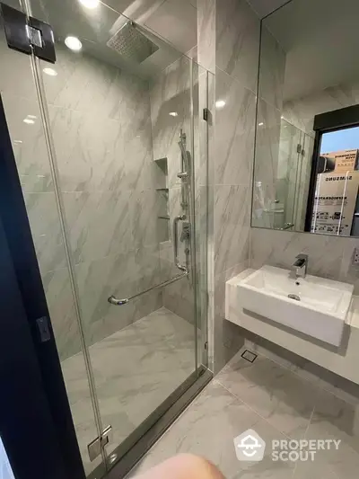 Modern bathroom with glass shower and sleek sink in luxury apartment