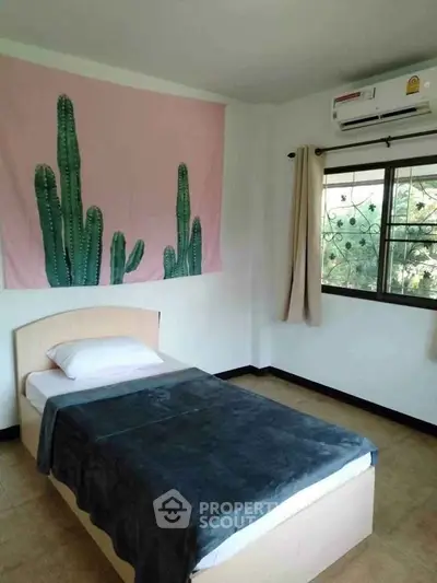 Cozy bedroom with single bed, cactus wall art, and air conditioning, perfect for a peaceful retreat.
