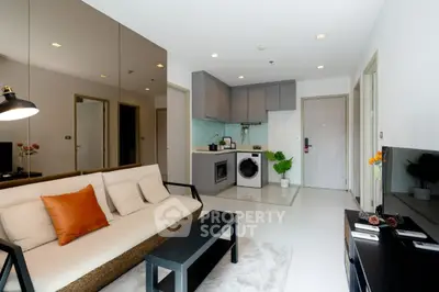 Modern living room with open kitchen, featuring sleek furniture and integrated appliances.