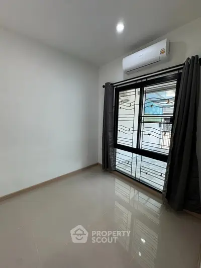 Spacious unfurnished room with large window and air conditioning, perfect for customization.
