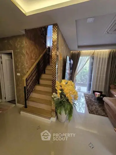 Elegant living room with staircase, modern decor, and large window view.
