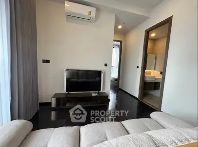 Modern living room with sleek design and open bathroom view, featuring a cozy sofa and wall-mounted TV.