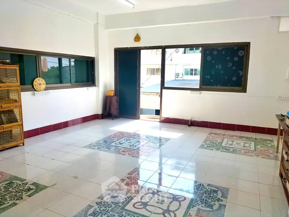 Spacious tiled room with large windows and natural light, ideal for versatile living space.