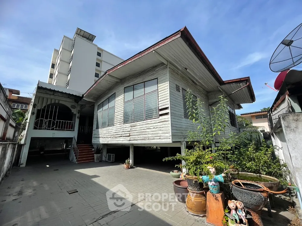 Charming traditional wooden house with spacious front yard and potted plants, perfect for serene living.