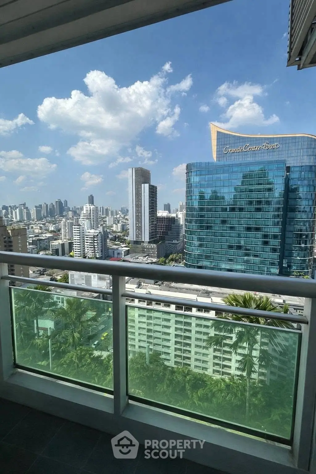 Stunning cityscape view from a high-rise balcony with modern architecture and clear blue skies.
