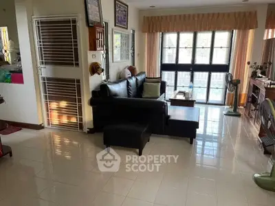 Spacious living room with natural light and modern black leather sofa