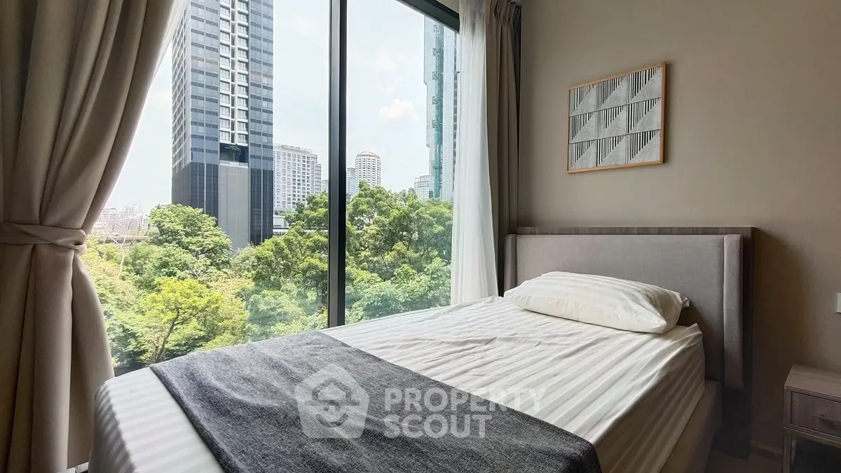 Modern bedroom with large window offering stunning cityscape and greenery views.
