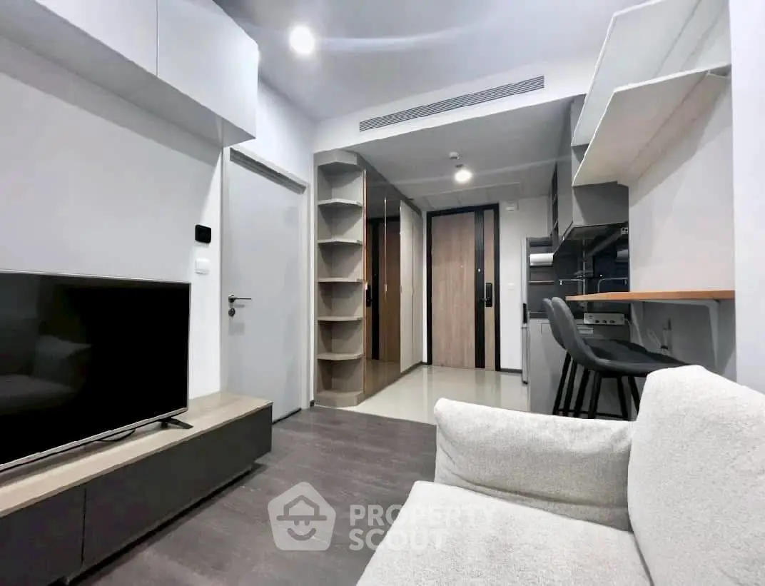 Modern living room with sleek furniture and open layout, featuring a cozy sofa and large TV.
