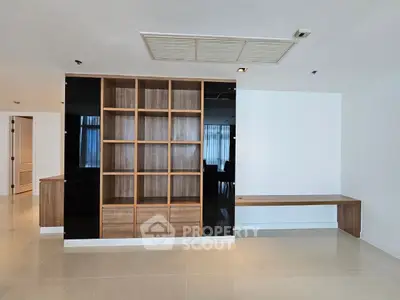 Spacious modern living room with built-in wooden shelving and sleek tile flooring.