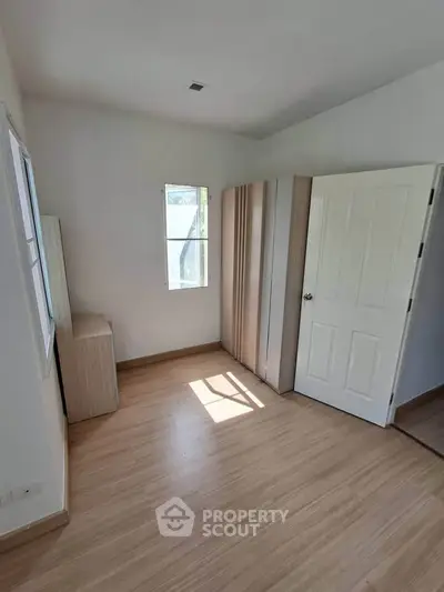 Bright and airy bedroom with wooden flooring and ample natural light.
