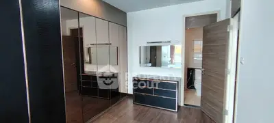 Modern bedroom with sleek mirrored wardrobe and stylish vanity, featuring a glimpse into an adjacent bathroom.