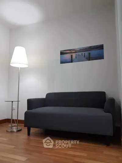 Modern living room with sleek gray sofa and stylish floor lamp on wooden flooring.