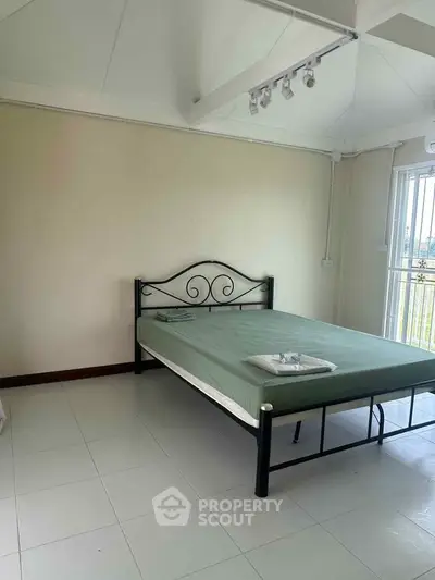 Spacious bedroom with metal bed frame and natural light, ideal for cozy living.
