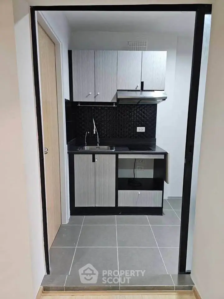 Modern compact kitchen with sleek cabinetry and stylish backsplash in a cozy apartment.