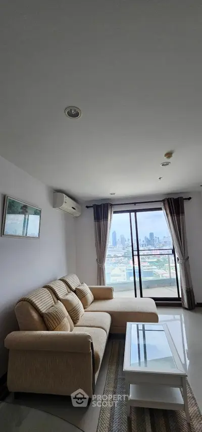Modern living room with city view, featuring a cozy sofa and glass coffee table.