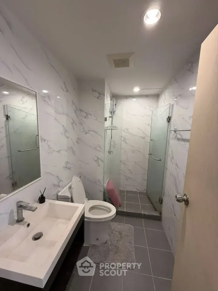 Modern bathroom with sleek design, glass shower, and marble walls in a contemporary home.